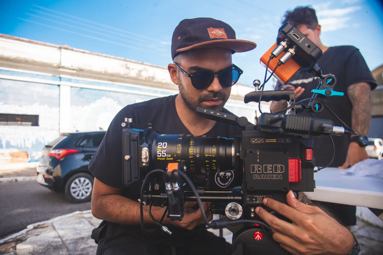 Dálio Marinho operating a RED cinema camera on a sunny street.