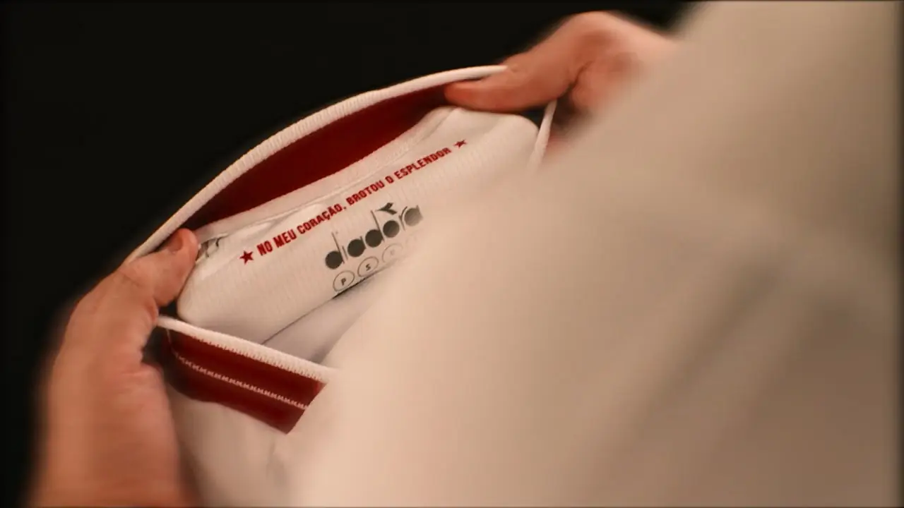 Hands opening the collar of a new Náutico football shirt in close-up.